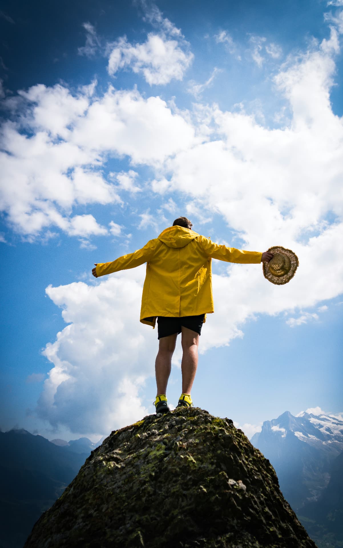Adventurer standing arms-wide on a summit above the clouds